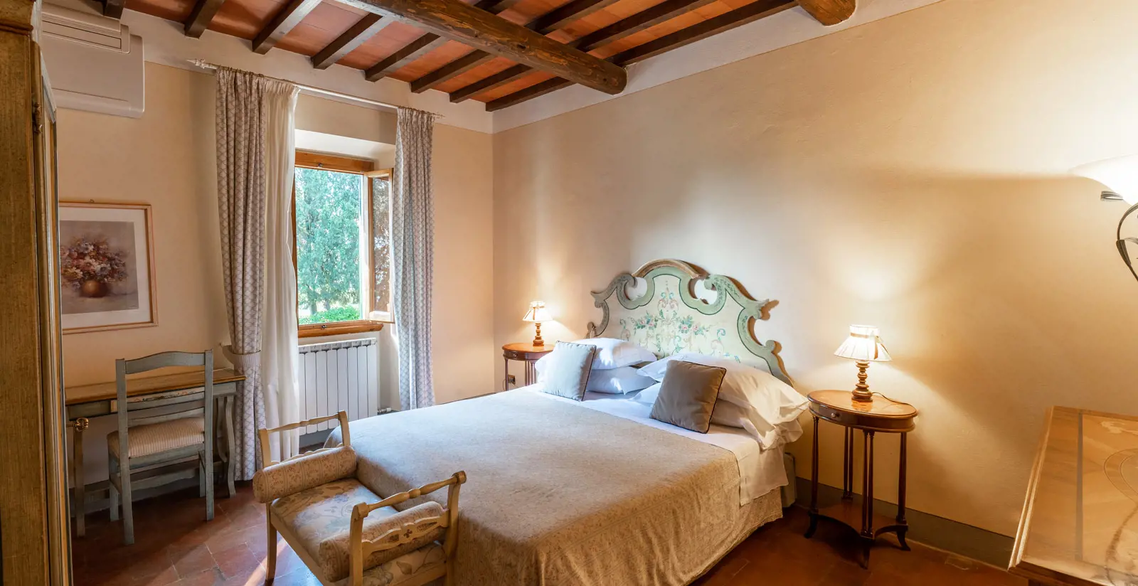 Guest room with a double bed, painted headboard and exposed beamed ceiling
