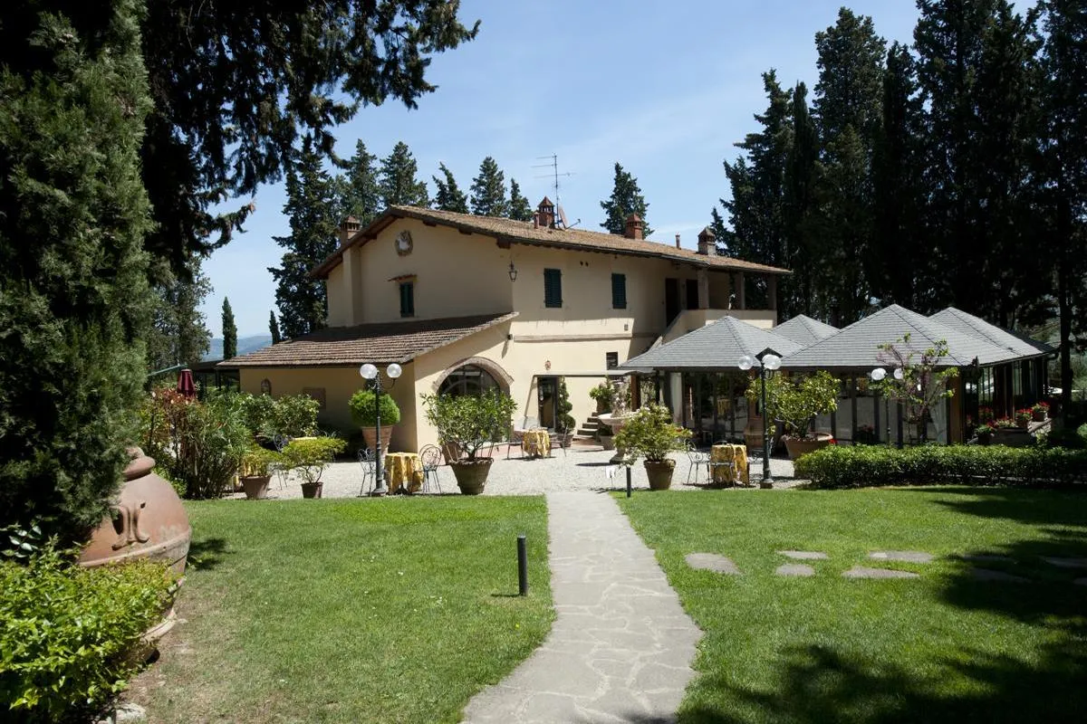 The Vecchio Borgo di Inalbi farmhouse seen from the lawn, with its veranda and garden tables